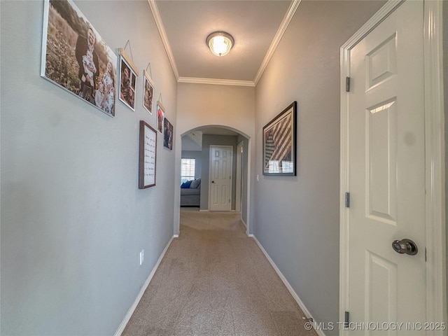 hallway with baseboards, arched walkways, light colored carpet, and crown molding