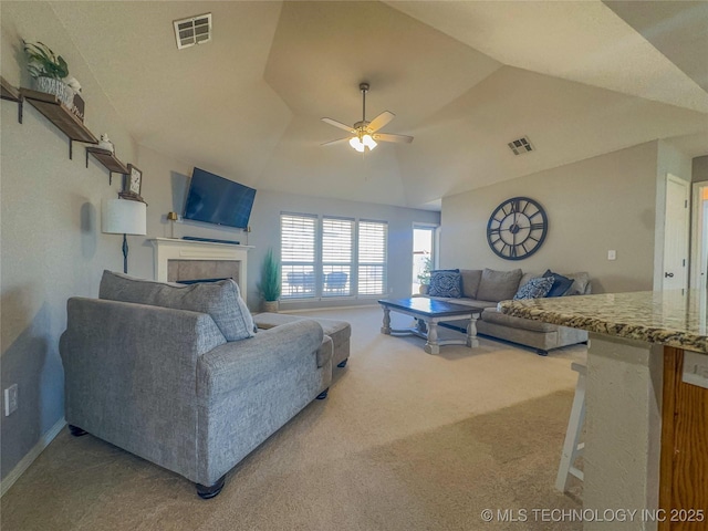 carpeted living room with a tiled fireplace, visible vents, ceiling fan, and vaulted ceiling