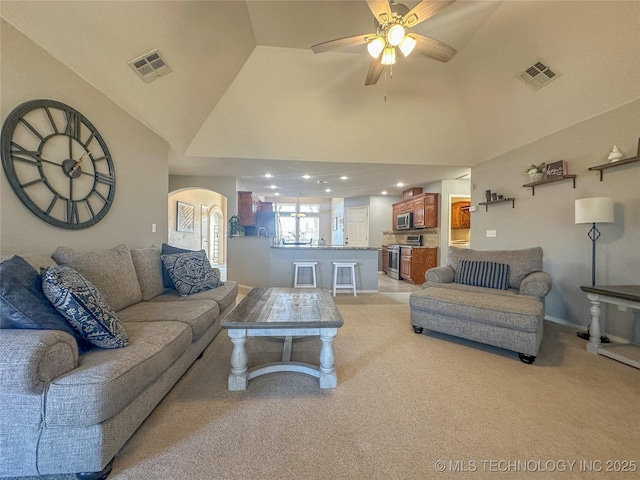 living area with light colored carpet, visible vents, high vaulted ceiling, and a ceiling fan