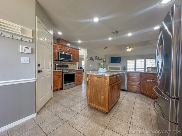 kitchen featuring a ceiling fan, backsplash, a center island, stainless steel appliances, and light tile patterned floors