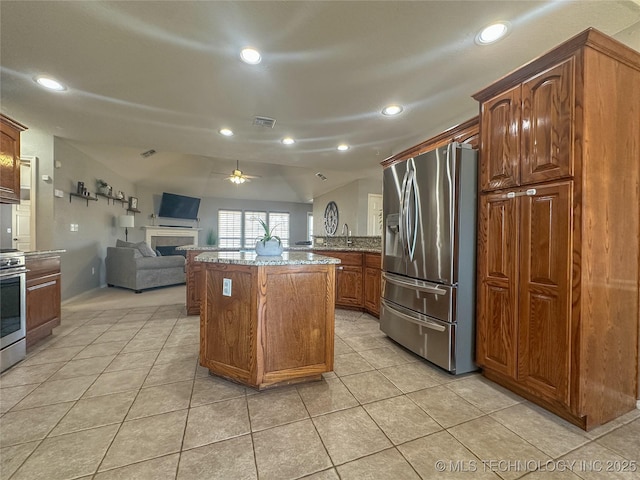 kitchen featuring a ceiling fan, visible vents, lofted ceiling, stainless steel fridge with ice dispenser, and a fireplace