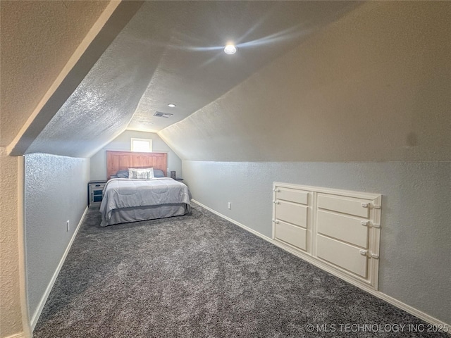 unfurnished bedroom with visible vents, lofted ceiling, a textured ceiling, carpet flooring, and a textured wall