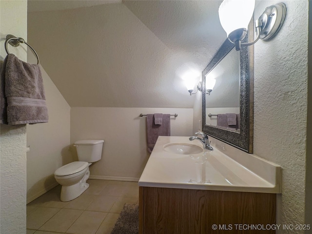 bathroom featuring tile patterned floors, toilet, baseboards, vanity, and vaulted ceiling