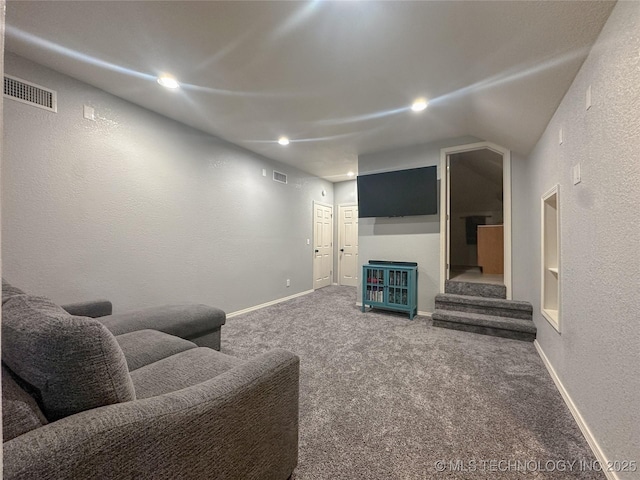 living area featuring visible vents, baseboards, carpet, and a textured wall