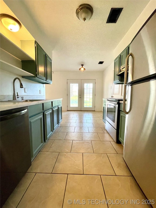 kitchen with green cabinets, light countertops, appliances with stainless steel finishes, french doors, and a sink