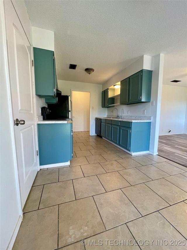 kitchen with visible vents, light tile patterned flooring, a sink, light countertops, and green cabinets