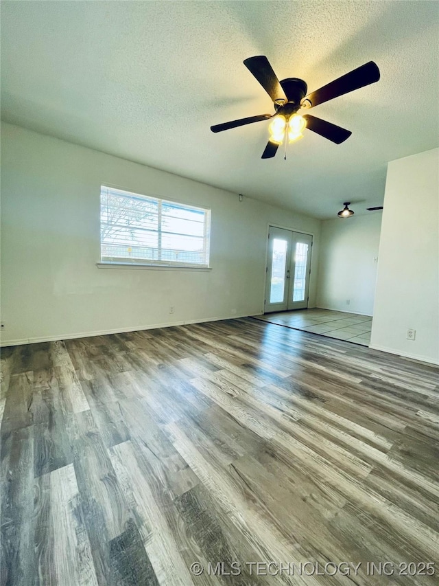 unfurnished room with baseboards, ceiling fan, french doors, wood finished floors, and a textured ceiling