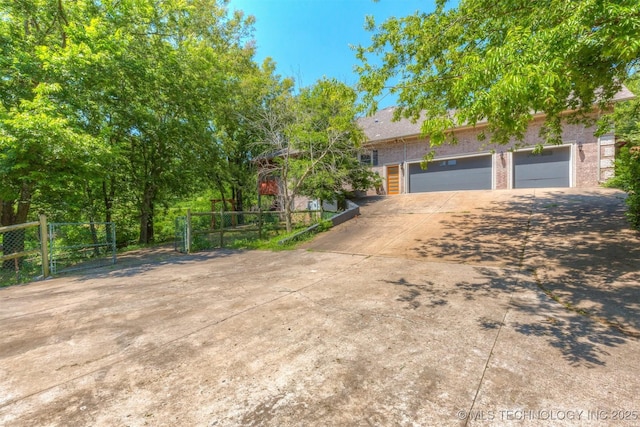 view of front of property featuring driveway, an attached garage, and fence