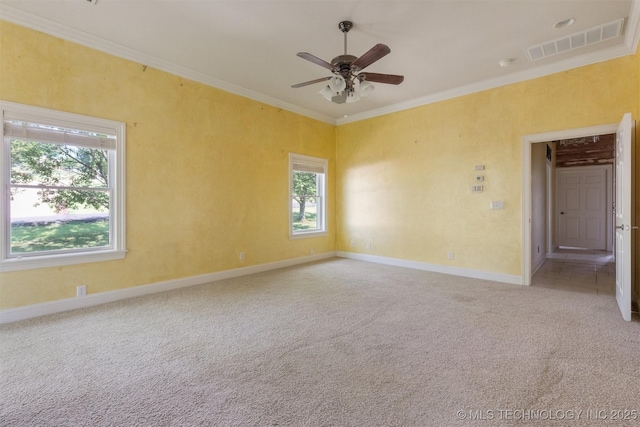 spare room featuring baseboards, visible vents, ceiling fan, crown molding, and light colored carpet