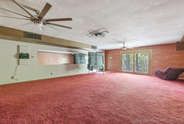 unfurnished living room featuring wood walls, carpet, and ceiling fan