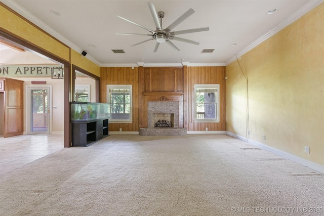 unfurnished living room featuring crown molding, a fireplace, light colored carpet, and a wealth of natural light