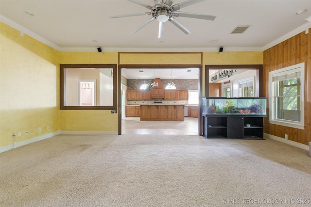 unfurnished living room with visible vents, light carpet, crown molding, baseboards, and ceiling fan