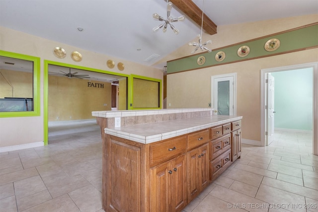 kitchen with tile countertops, light tile patterned floors, vaulted ceiling with beams, ceiling fan, and brown cabinets