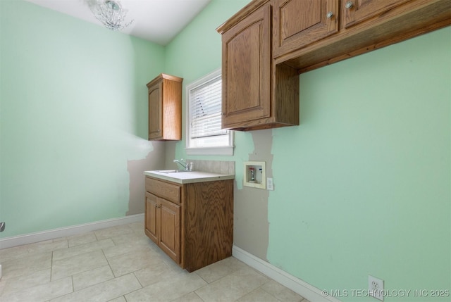 laundry area featuring a sink, baseboards, cabinet space, and washer hookup