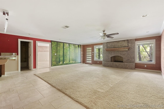 unfurnished living room with a wealth of natural light, visible vents, a ceiling fan, and a fireplace