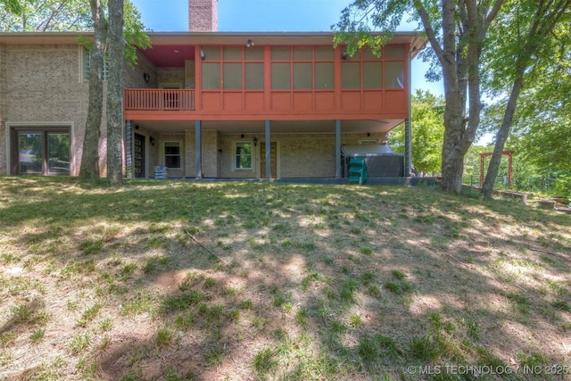 back of property featuring brick siding, a lawn, and a chimney