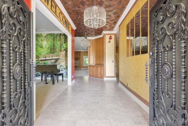 foyer with light carpet, ornamental molding, an ornate ceiling, baseboards, and a chandelier