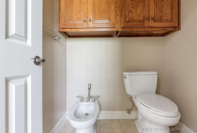 bathroom with tile patterned floors, toilet, a bidet, and baseboards