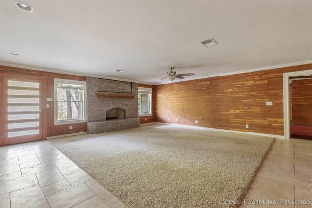 unfurnished living room featuring a fireplace, crown molding, a ceiling fan, and visible vents