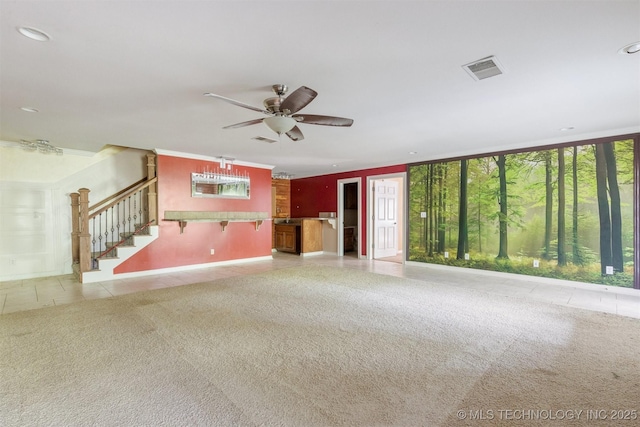 unfurnished living room featuring stairway, visible vents, ceiling fan, tile patterned flooring, and carpet flooring