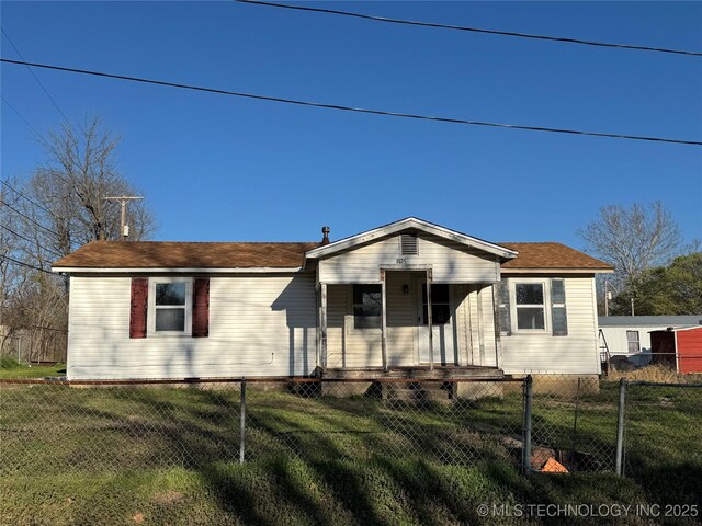 view of front of property featuring a front lawn, covered porch, a fenced front yard, and a shingled roof