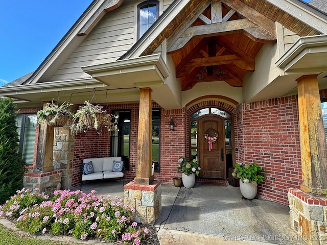 view of exterior entry featuring brick siding and a porch