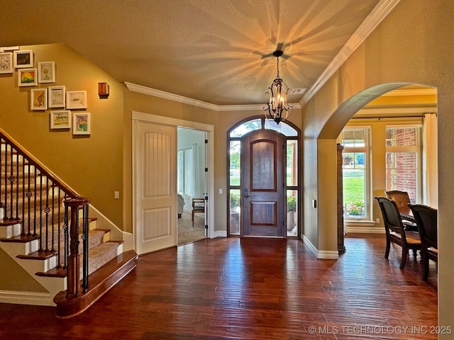 entrance foyer featuring arched walkways, wood finished floors, stairs, and crown molding