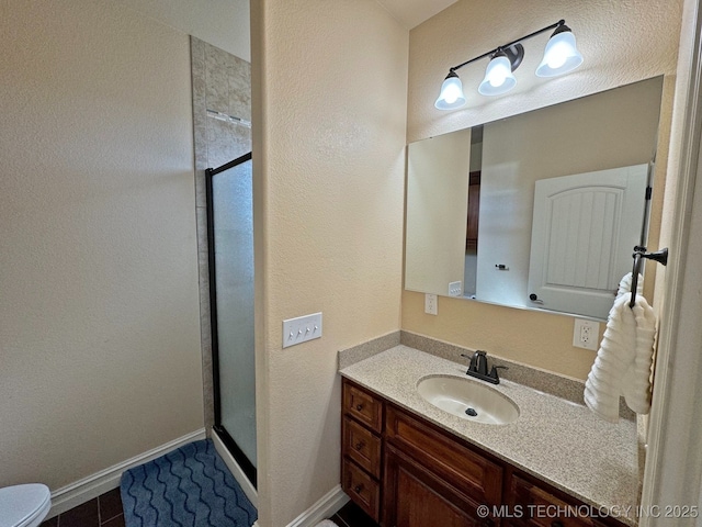 bathroom featuring toilet, a stall shower, vanity, and baseboards