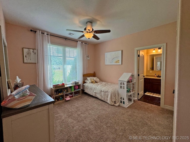 bedroom with visible vents, a textured ceiling, dark carpet, connected bathroom, and ceiling fan
