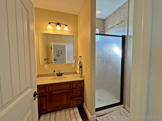 bathroom with vanity, baseboards, and a stall shower
