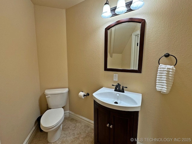 half bathroom with tile patterned flooring, toilet, vanity, and baseboards