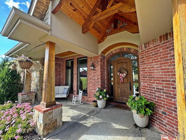 doorway to property with brick siding and a porch