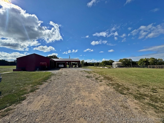 exterior space with an outbuilding, a yard, fence, and driveway