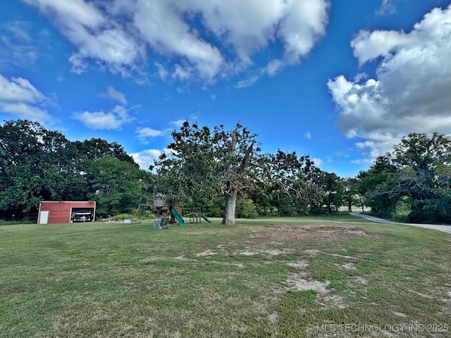 view of yard featuring playground community and a detached garage