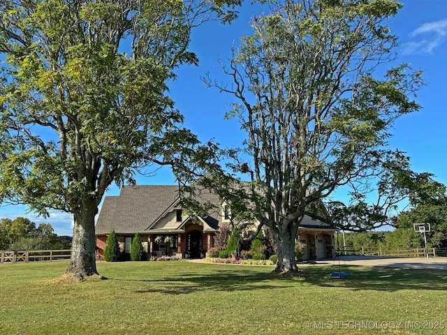 view of front of home featuring driveway, a front lawn, and fence
