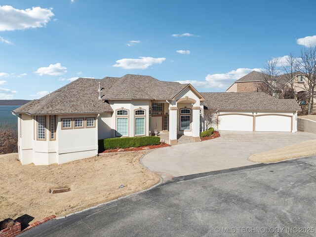 view of front of property featuring stucco siding, a garage, roof with shingles, and driveway