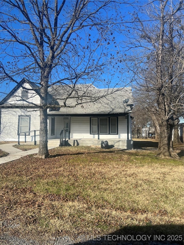 ranch-style home featuring covered porch and a front lawn