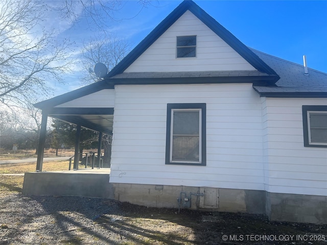 view of home's exterior with a porch and roof with shingles
