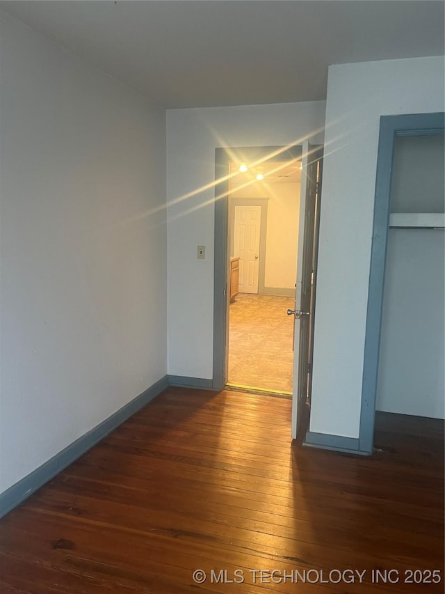hallway featuring baseboards and hardwood / wood-style floors