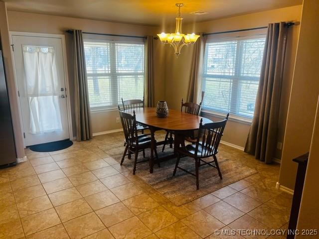 dining area with light tile patterned floors, baseboards, and a chandelier