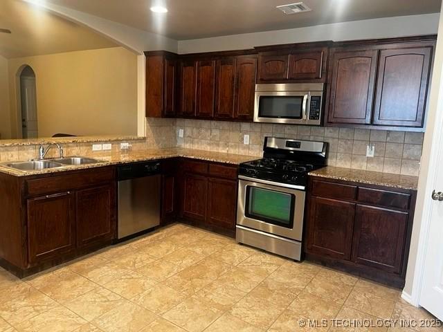 kitchen with light stone counters, visible vents, appliances with stainless steel finishes, and a sink