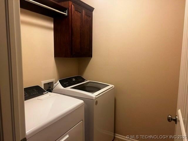 laundry room with washing machine and clothes dryer and cabinet space