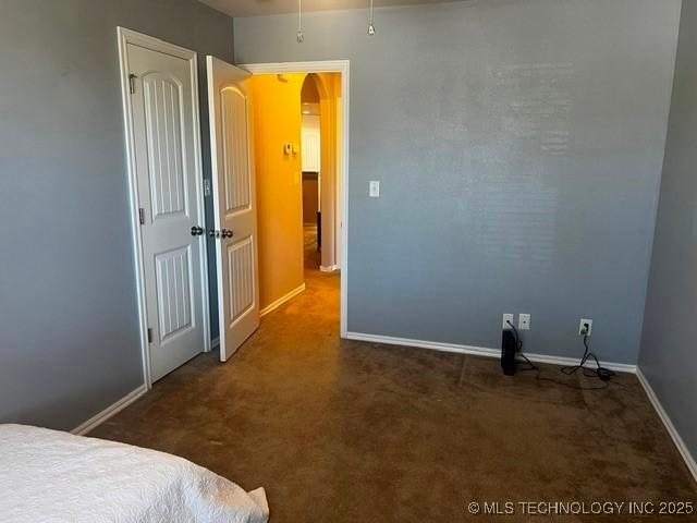 unfurnished bedroom with carpet flooring, baseboards, and arched walkways