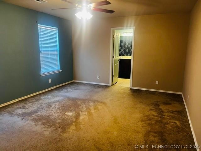 carpeted empty room featuring a ceiling fan and baseboards