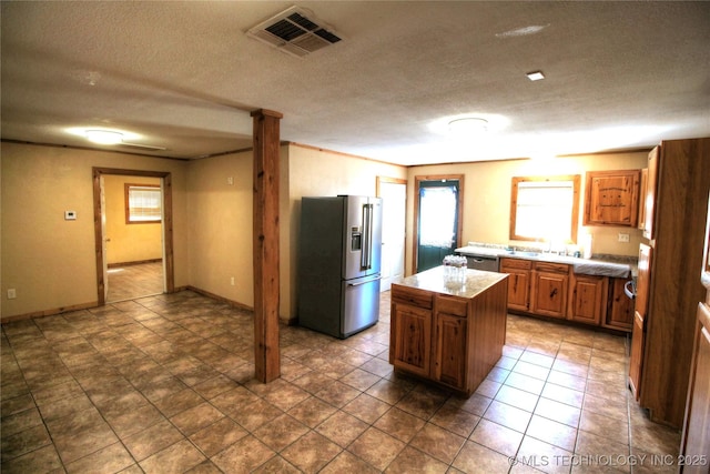 136 Pine St, Mead, OK 73449 - kitchen with visible vents, a kitchen island, appliances with stainless steel finishes, a textured ceiling, and brown cabinets