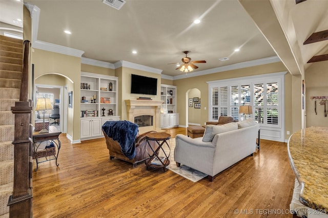 living area featuring light wood-style floors, visible vents, arched walkways, and a glass covered fireplace