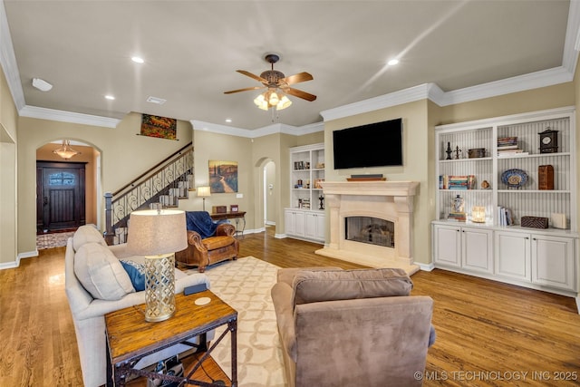 living area featuring stairway, ceiling fan, arched walkways, and wood finished floors
