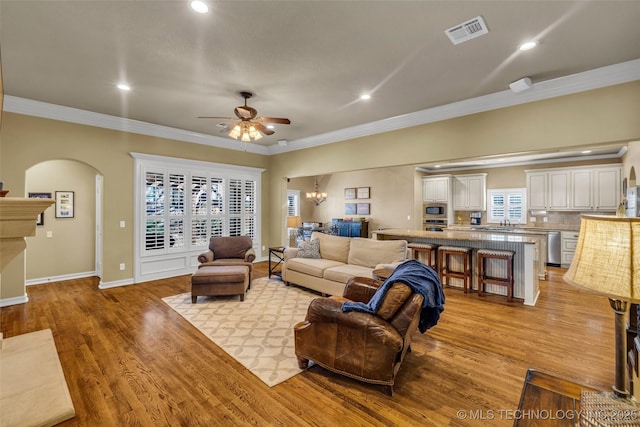 living area featuring visible vents, ceiling fan, arched walkways, ornamental molding, and recessed lighting