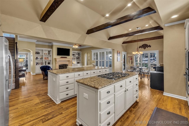 kitchen featuring light wood-style flooring, a center island, open floor plan, stainless steel appliances, and vaulted ceiling with beams