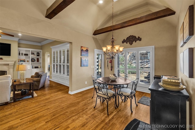 dining space featuring wood finished floors, a fireplace, lofted ceiling with beams, baseboards, and recessed lighting